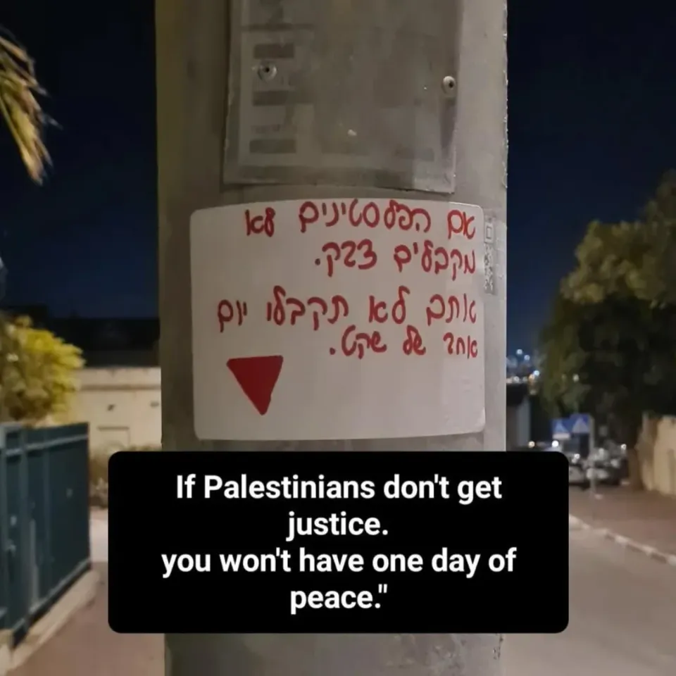 Tom's anti-Zionist sticker placed in occupied West Bank, which says, "If Palestinians don't get justice, you won't have one day of peace" with a red triangle.